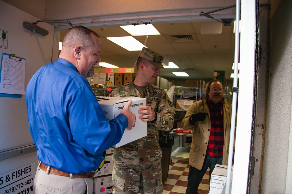 Keith Jackson hands LTC Trent Colestock a box of canned goods at the food drive drop off.