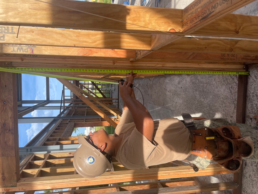 Builder 3rd Class Carlos Hernandez  uses a tape measure to ensure correct placement for the door header for the Richardson Multipurpose Facility.