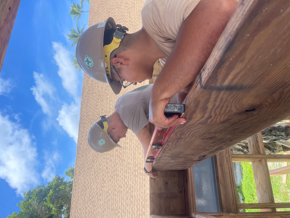 Builder 3rd class Carlos Hernandez, and Utilitiesman 3rd Class Michael Klemczak, levels ceiling rafters for the Richardson Multipurpose Facility.