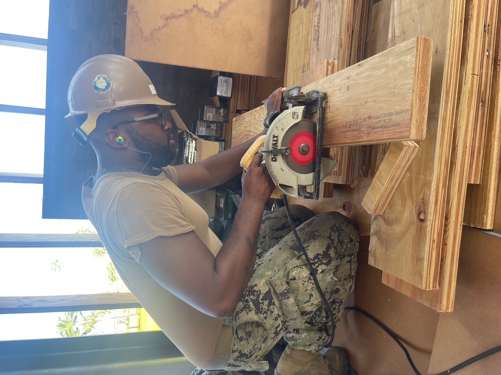 Equipment Operator 3rd Class Bobby Smith, uses a circular saw to cut blocking for the wall studs of The Richardson Multipurpose Facility.
