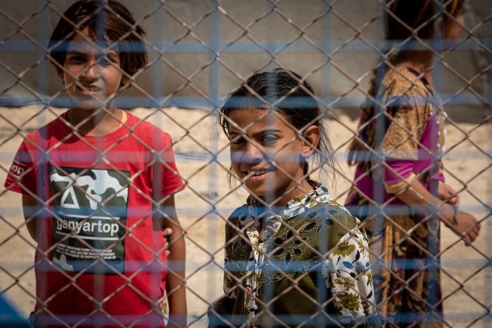 Young girls look to a US Civil Affairs team through the fence at al Hol camp