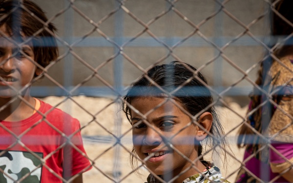 Young girls look to a US Civil Affairs team through the fence at al Hol camp