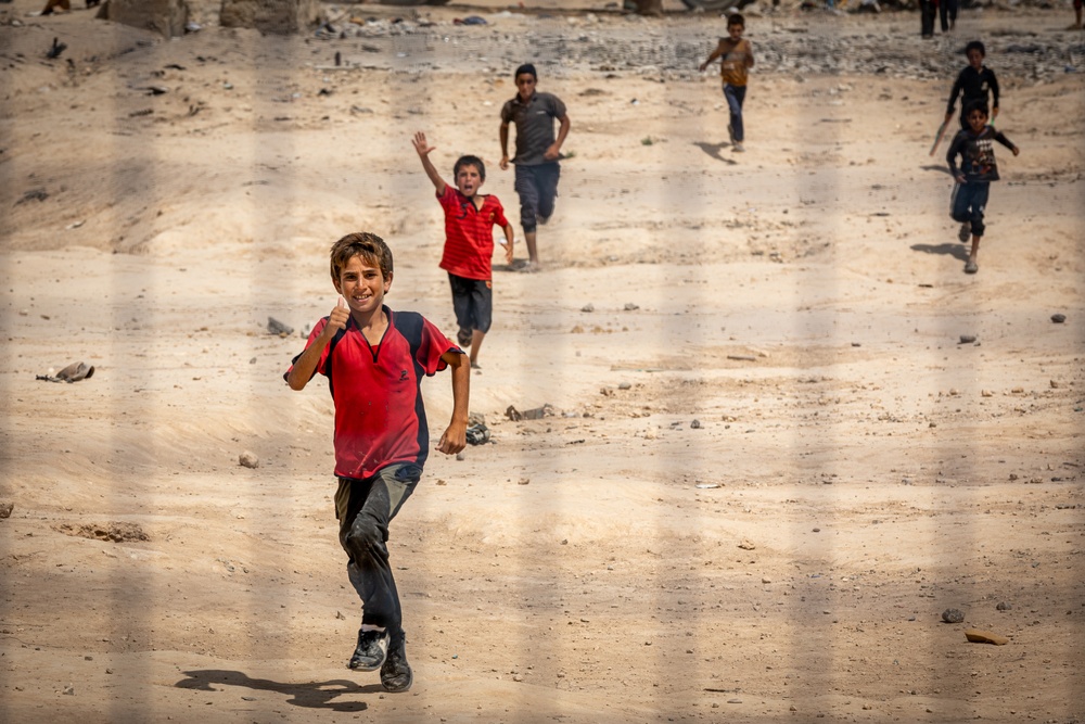 Children greet a US Civil Affairs team at a visit to al Hol camp