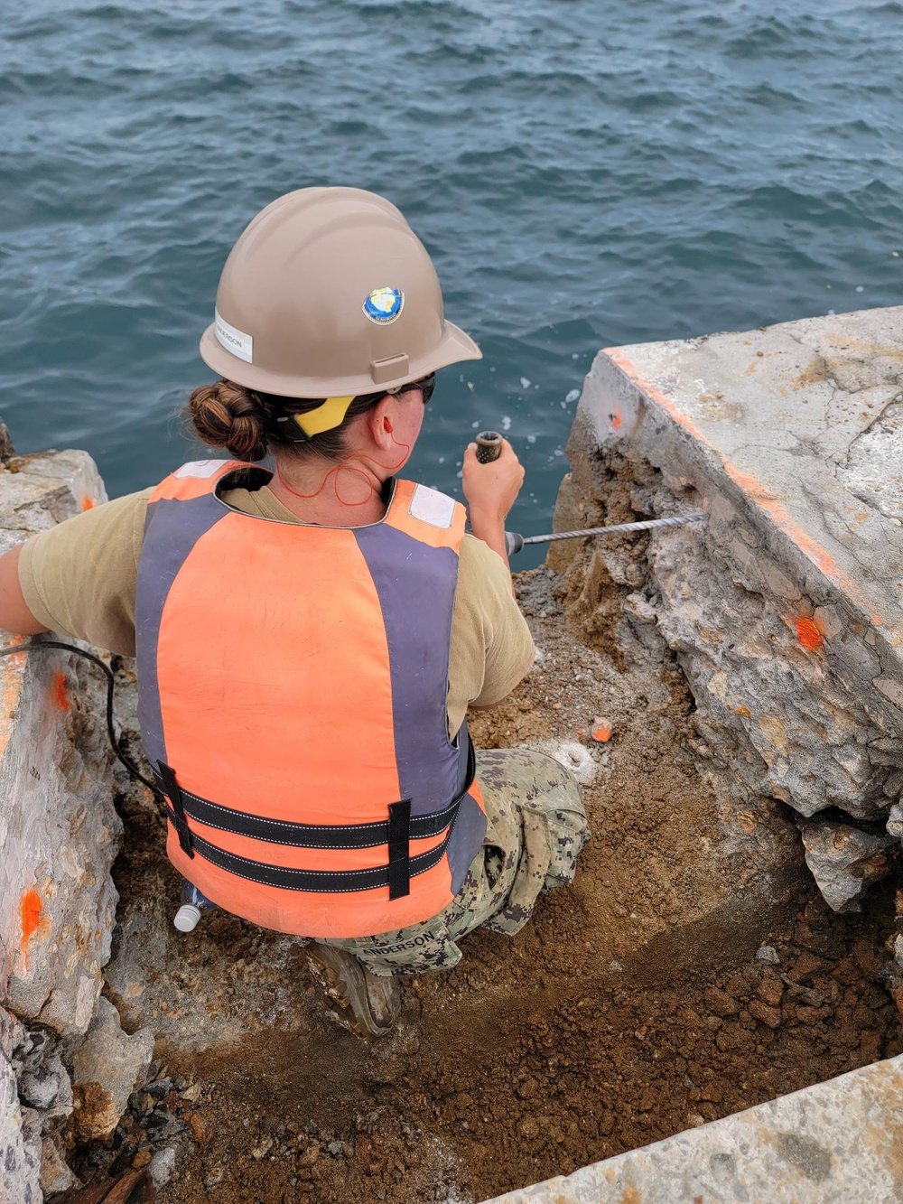 Equipment Operator 3rd Class Madison Anderson, drills holes for a rebar cages part of the Malakal Harbor Improvements Project.