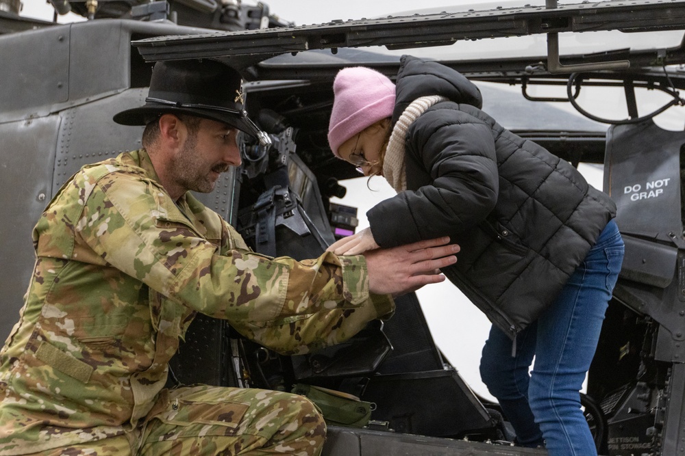 AH-64 Apache Pilot helps Polish Elementary School student into a AH-64 Apache