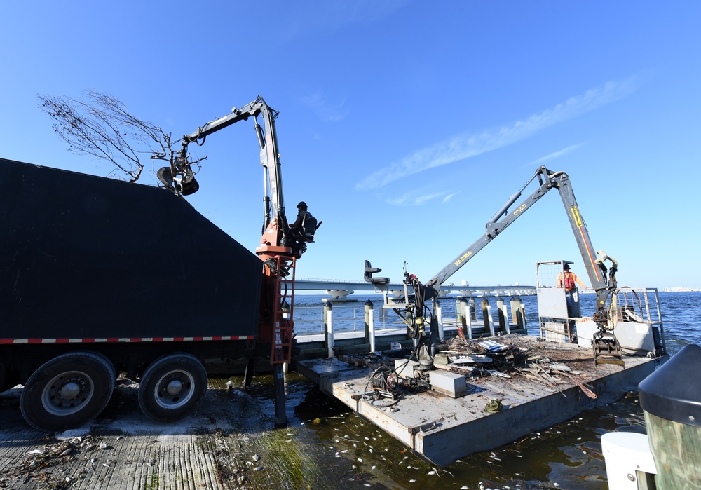 Crews Work To Clear Debris Off Of A Barge That Has Collected Debris in Waterways