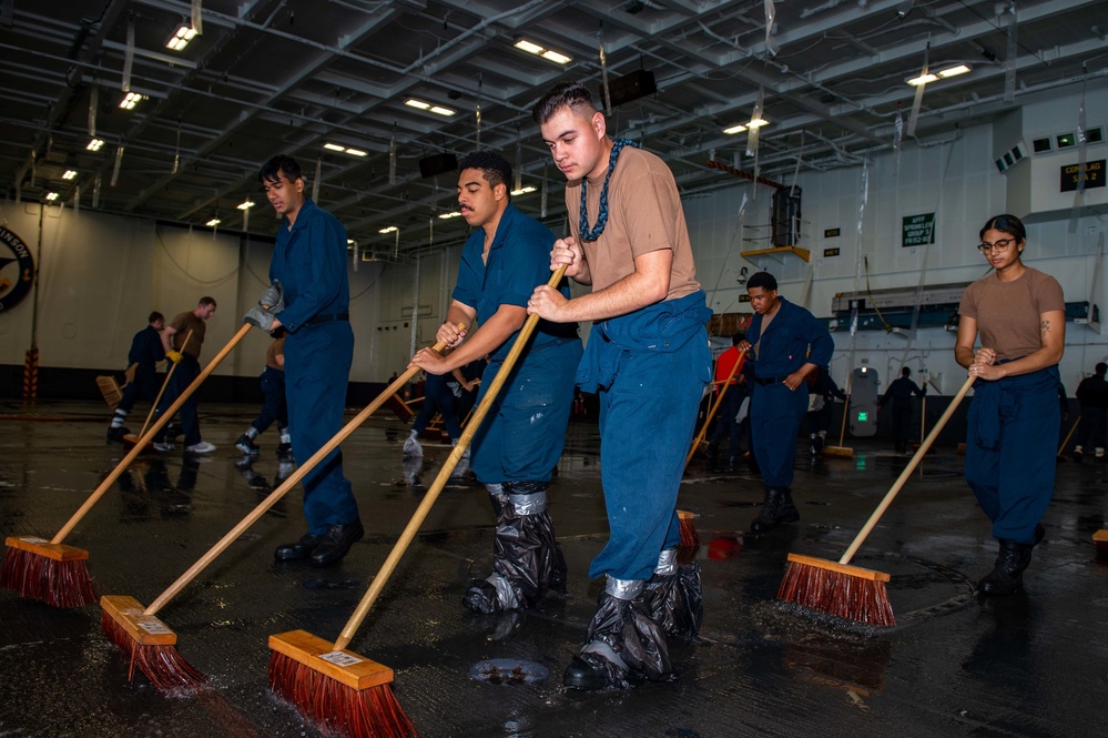 Sailors Scrub The Hangar Deck During a Sprinkler Test