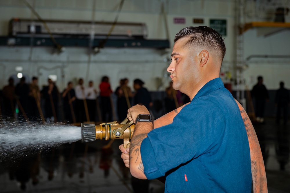 Sailor Sprays Down The Hangar Deck During a Sprinkler Test Aboard CVN 70