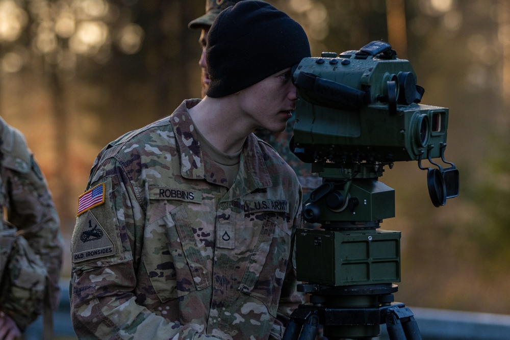 Pfc. Robbins lookin through a German viewfinder at the firing point of the call for fire mission
