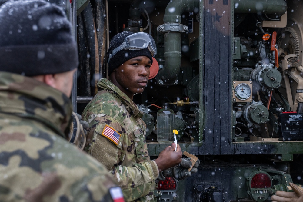 U.S. Army Soldier displays a fuel test pad to Polish Soldiers during a combined fuel test exercise