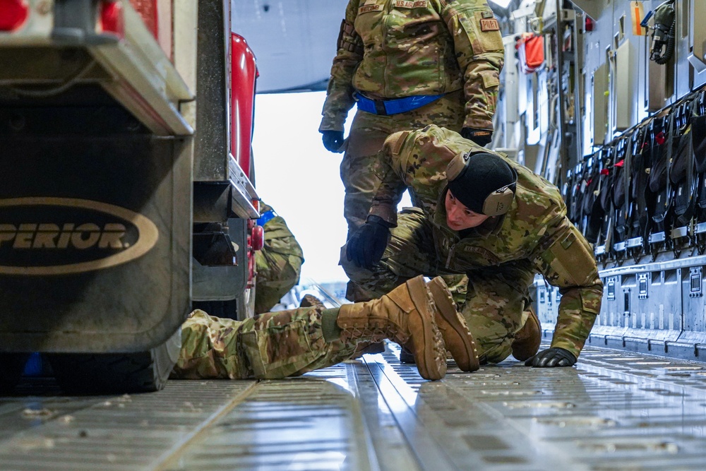 Aerial porters tie down a firetruck to a C-17