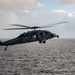 A MH-60S Sea Hawk passes Nimitz-class aircraft carrier USS Carl Vinson