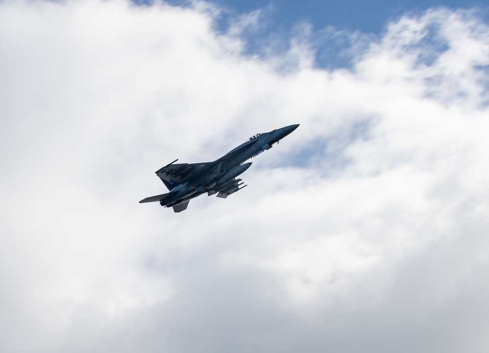 ) A F/A-18E Super Hornet flies over Nimitz-class aircraft carrier USS Carl Vinson