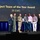 350th Spectrum Warfare Wing Crows awarded at AOC A group of approximately seven men are standing on a stage receiving the 'Project Team of the Year Award' for 39 EWS, as displayed on a large screen behind them. Two individuals in military uniforms (one in flight suit, one in Army Combat Uniform) are present alongside civilians. One person is holding a framed award/plaque during the ceremony.