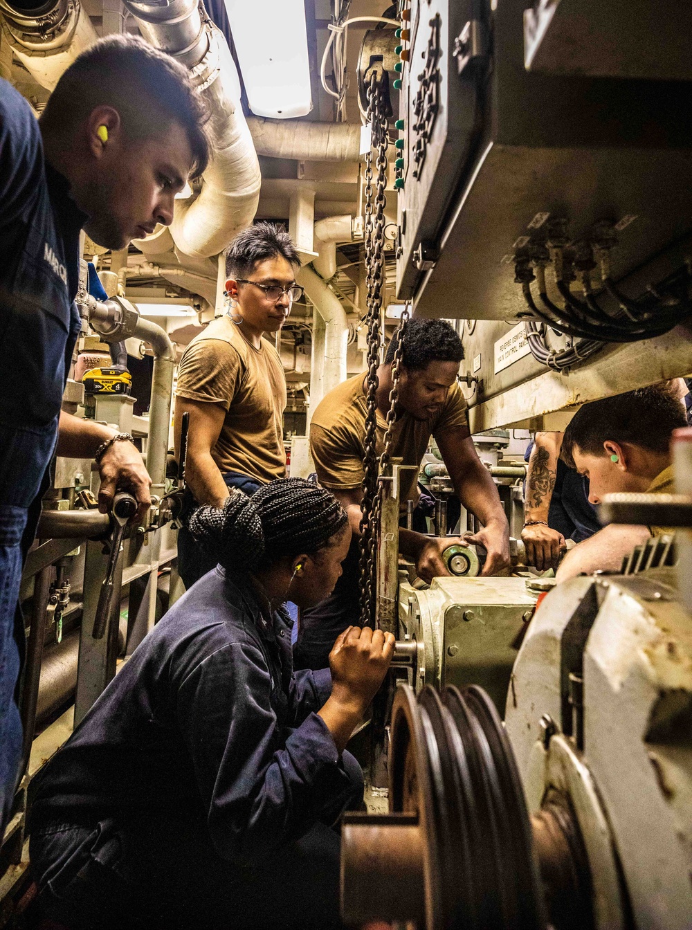 U.S. Navy Sailors replace pump in reverse osmosis water unit.