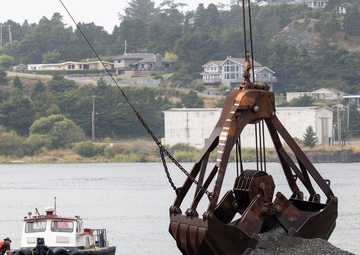 Workers dwarfed by Clamshell Dredge bucket at the mouth of the Rouge River, Ore.