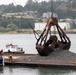 Workers dwarfed by Clamshell Dredge bucket at the mouth of the Rouge River, Ore.