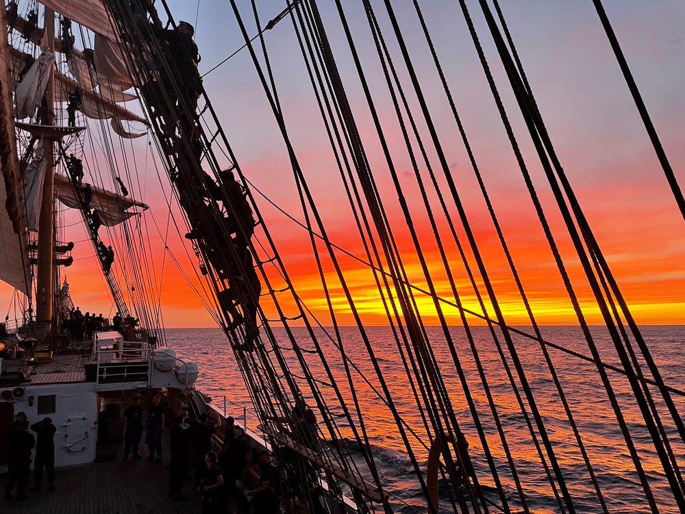 Dousing sail onboard USCGC Eagle in the setting sun