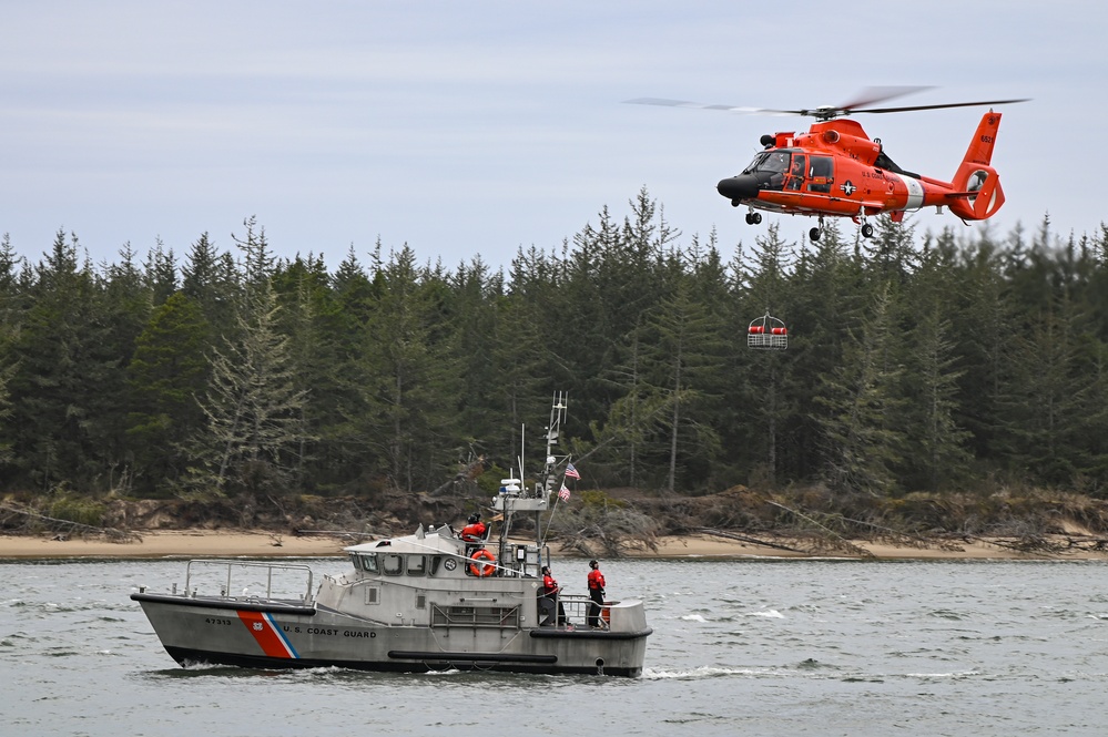 An aircrew aboard an MH-65E Dolphin helicopter from Coast Guard Sector North Bend conducts hoist training with a crew aboard a 47-foot Motor Lifeboat from Coast Guard Station Umpqua River while transiting near Winchester Bay, Oregon, March 14, 2015. Aircrews and boat crews regularly train together ensure both units are ready to respond during an emergency. (U.S. Coast Guard photo by Petty Officer Steve Strohmaier)