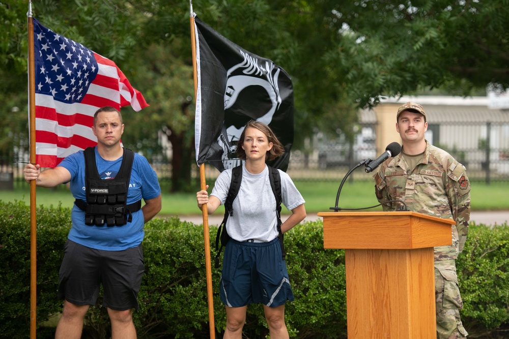 Airman holds flags during POW/ MIA ruck marxh