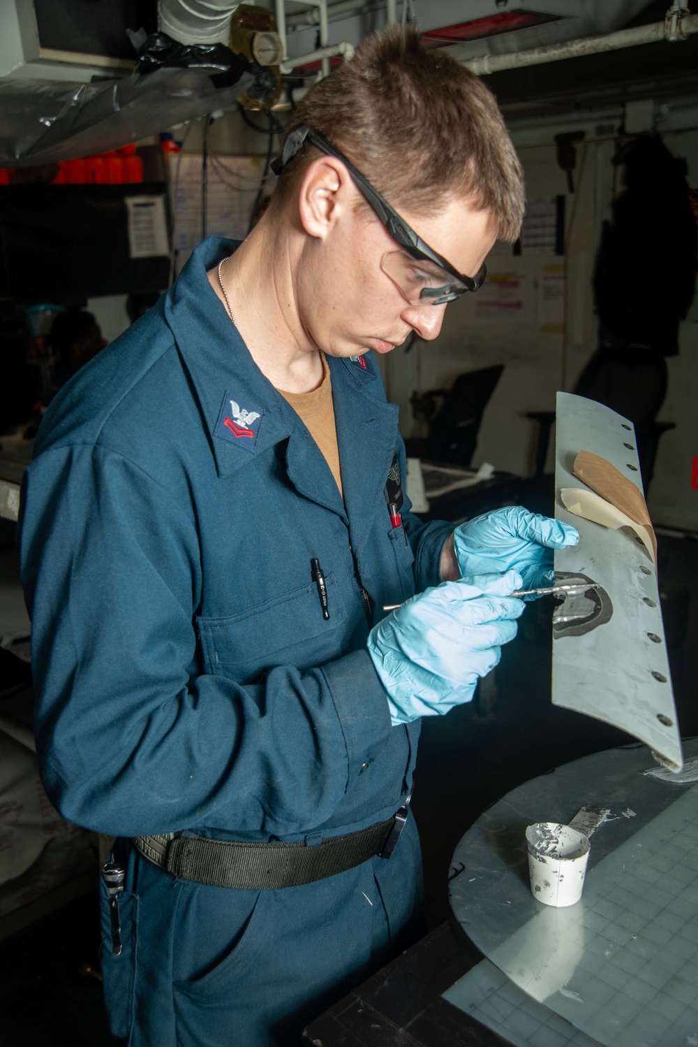 Sailor Applies Adhesive To Aircraft Panel