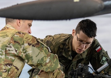 U.S Army Soldier shows Polish Military an AH-64 Apache