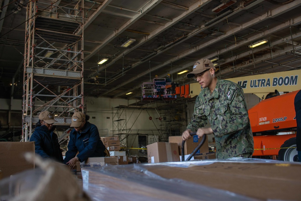 USS Ronald Reagan (CVN 76) Sailors move cargo in the hangar bay