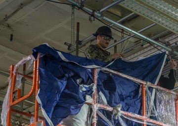 USS Ronald Reagan (CVN 76) Sailors hang banner in the hangar bay