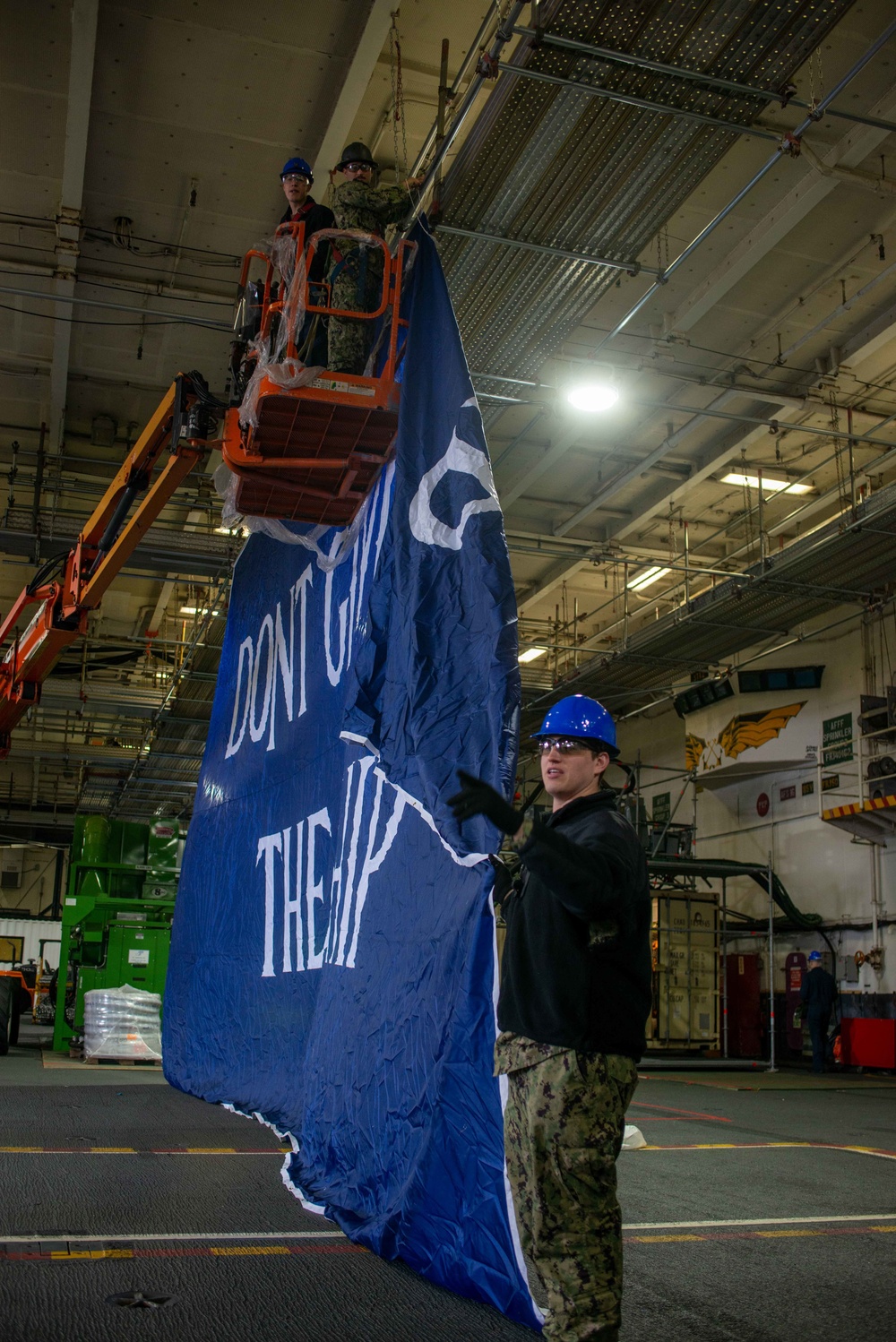 USS Ronald Reagan (CVN 76) Sailors hang banner in the hangar bay