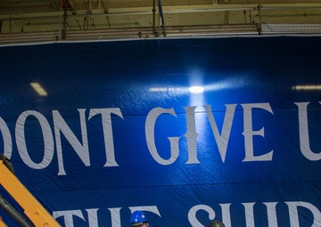 USS Ronald Reagan (CVN 76) Sailors hang banner in the hangar bay