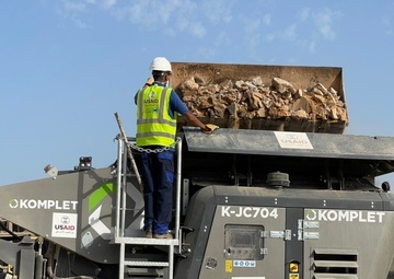 A Worker Helps Drop Rubble into a USAID-Provided Jaw Crusher in Abuselim, Libya
