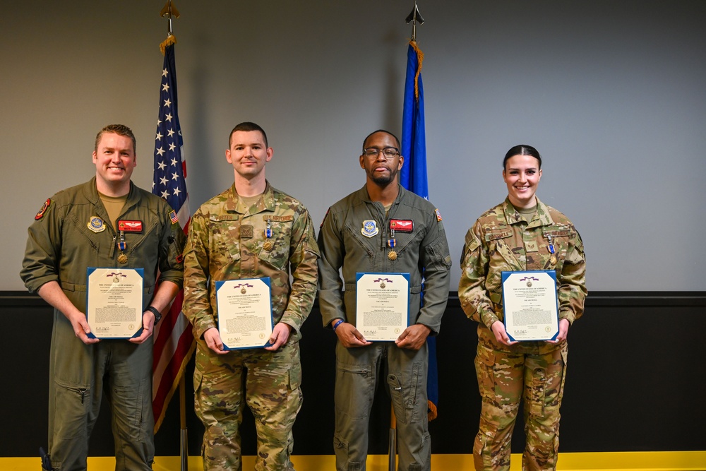 U.S. Airmen gather for a group photo holding their Air Medal citations during a ceremony.