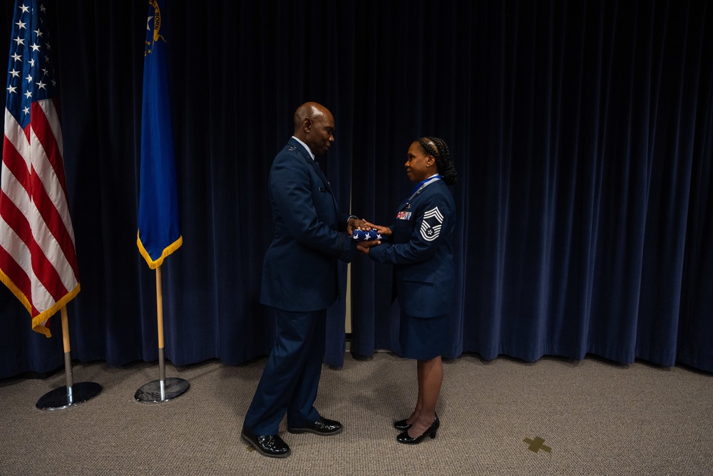 Maj. Gen. Ondra L. Berry presents Chief Master Sgt. Angela D. Ash with an American Flag at her retirement ceremony