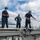 Sailors slack lines during line handling operations in preparation for mooring from the flight deck