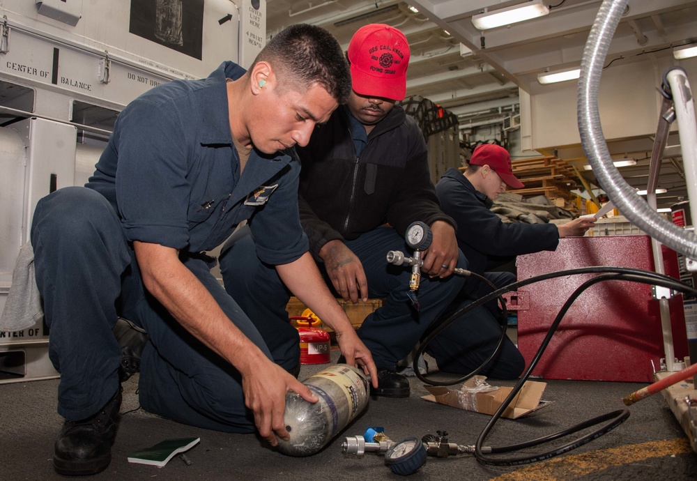 Sailors perform maintenance on an air compressor