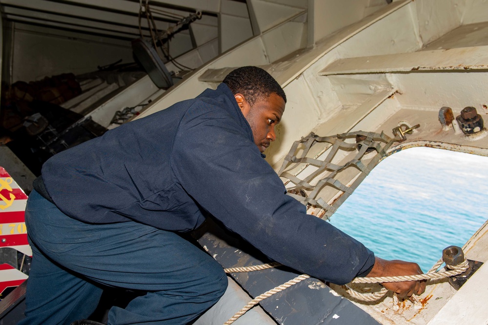 Sailor attaches the messenger in preparation for mooring in the Forecastle