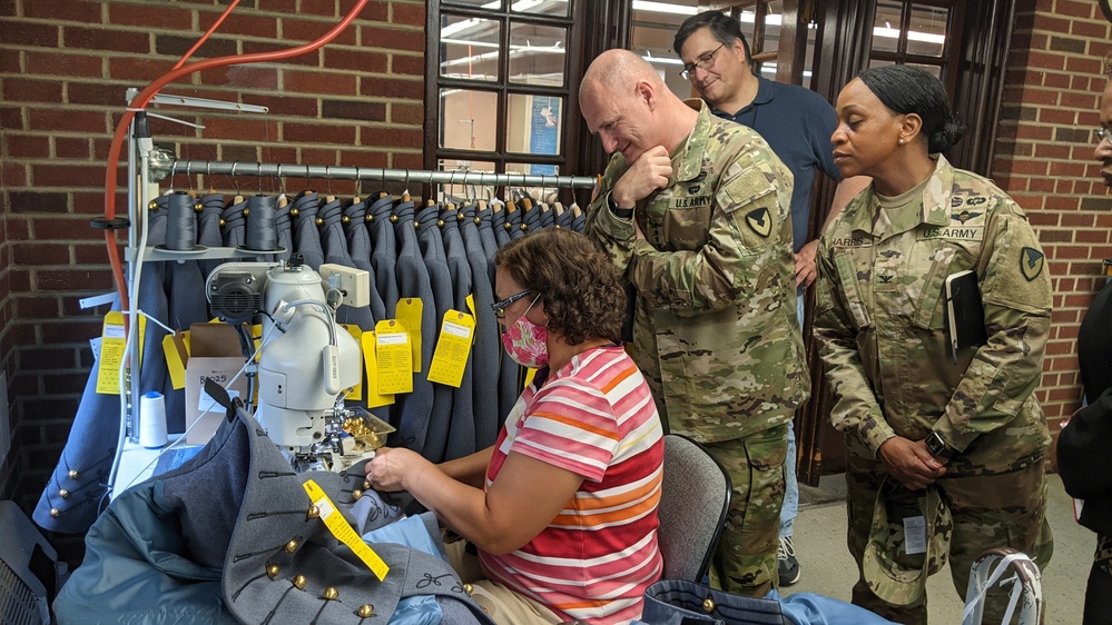 A West Point Cadet Uniform Factory staff member stitches a cadet uniform as AMC Commander Gen. Edward Daly observes