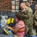A West Point Cadet Uniform Factory staff member stitches a cadet uniform as AMC Commander Gen. Edward Daly observes