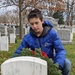 A child places a wreath against a grave stone during a Wreaths Across America event at the West Point cemetery