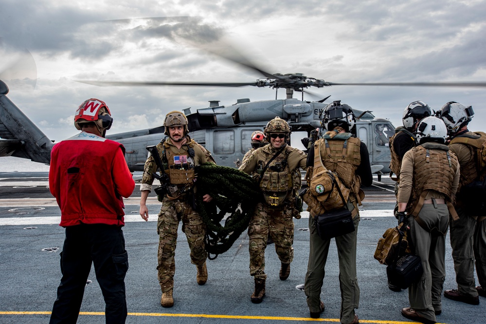 U.S. Navy Sailors Unload Gear From A Helicopter