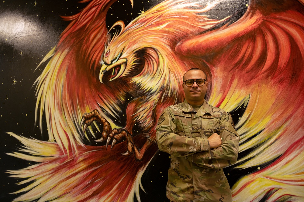 Airman 1st Class Alvin Auffant, paints mural representing squadron resilience in achieving initial operating capability