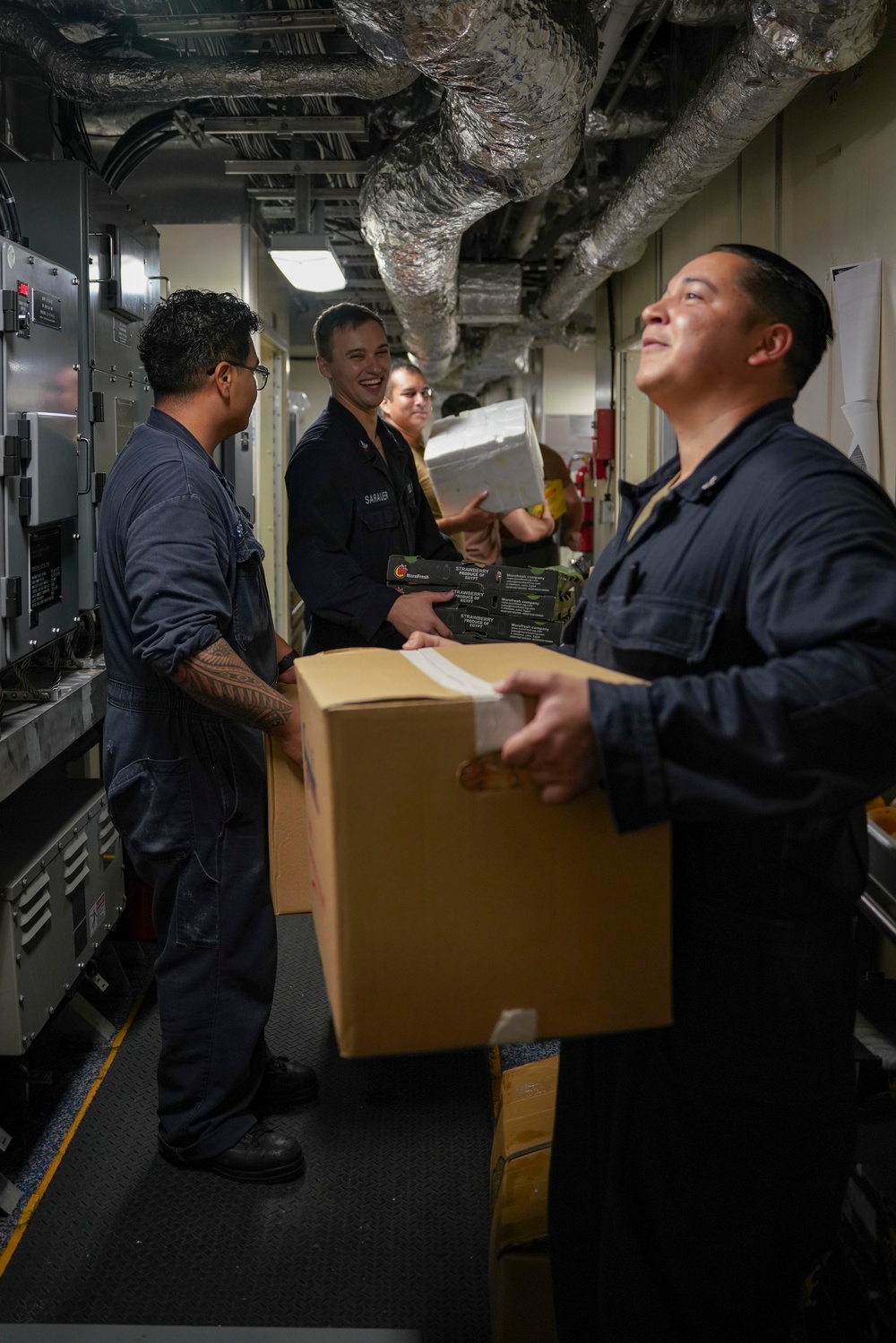 Sailors Move Supplies In a Working Party Aboard USS Oakland