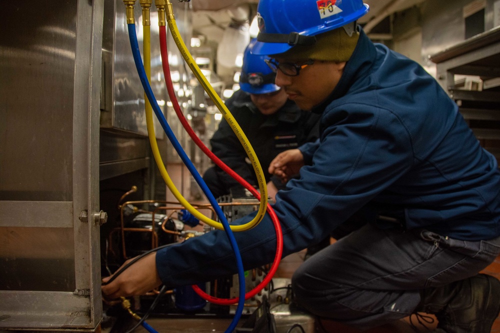 USS Ronald Reagan (CVN 76) Sailors transport cargo in the hangar bay