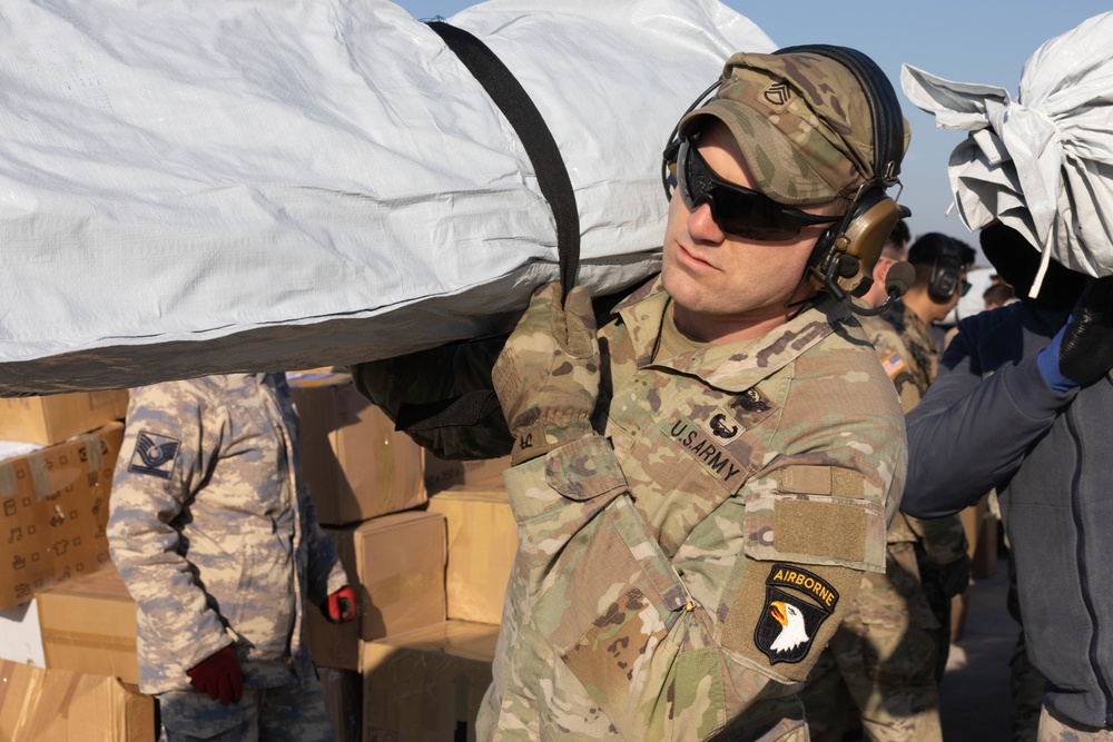 A US Army Soldier loads a CH-47 Chinook with humanitarian aid supplies