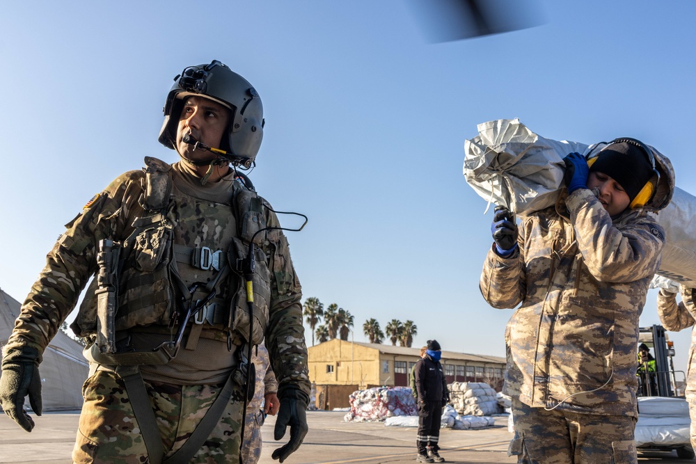 A US Army Soldier supervises loading a CH-47 Chinook with humanitarian aid supplies