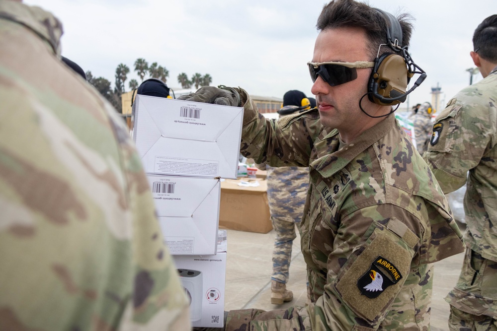 A US Army Soldier loads a CH-47 Chinook with humanitarian aid supplies