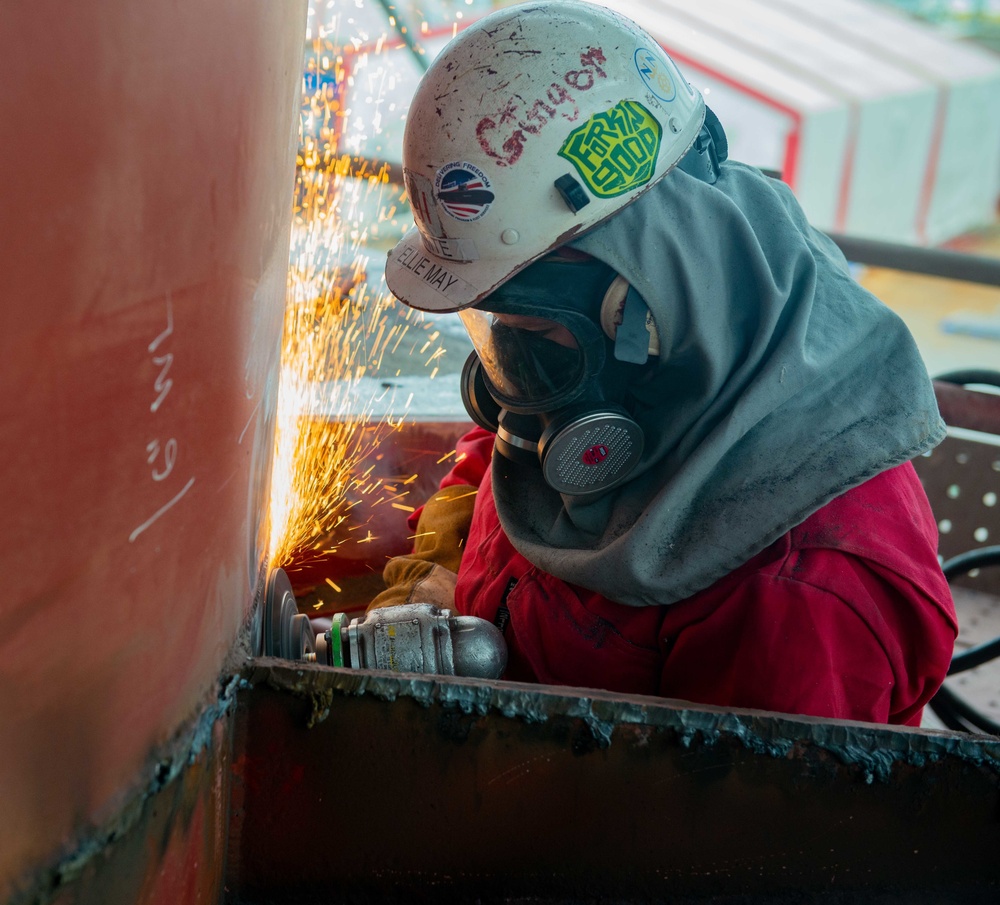 Contractor grinds metal aboard the USS John C. Stennis