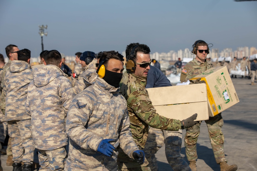 U.S. Army Soldier helps load CH-47F Chinook with humanitarian aid supplies