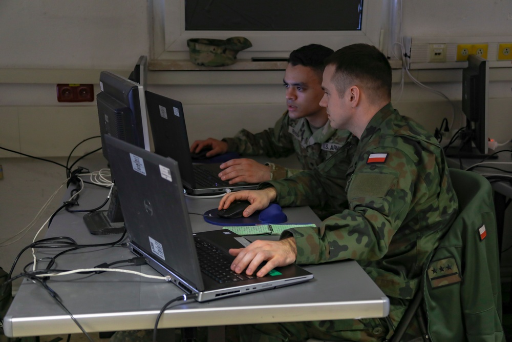 U.S. Army 12th CAB Soldier Assists Polish soldier During JCATS Training