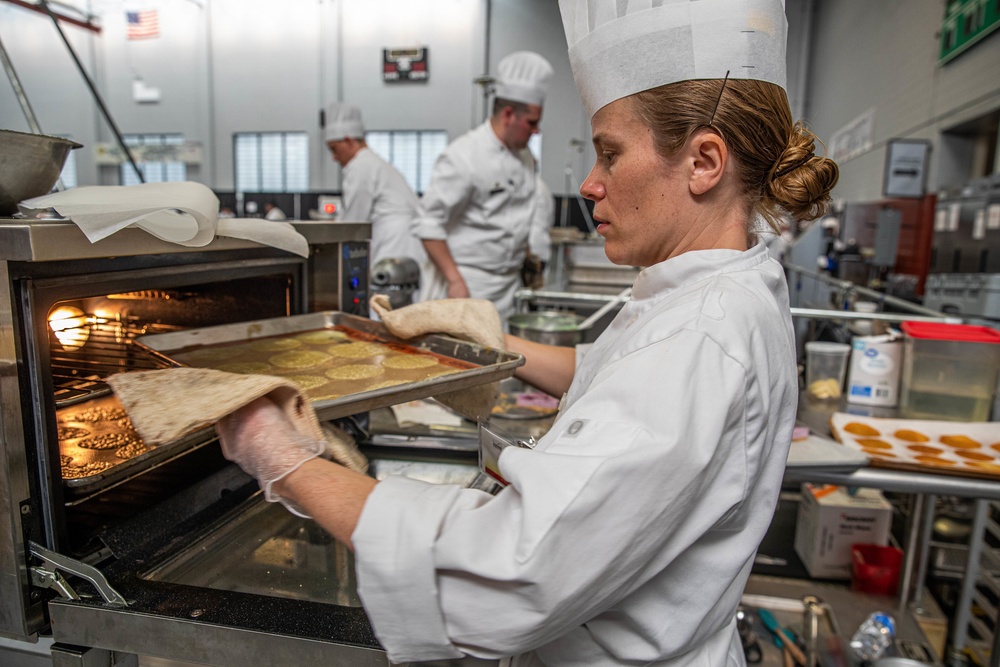 Chief Warrant Officer 2 Christine Stanley puts a citrus tuille into an oven